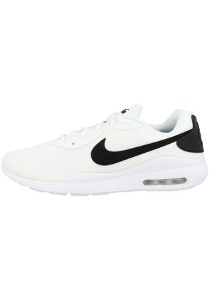 Baskets blanches de sport avec logo Nike swoosh noir et amorti à air visible dans la semelle, vues de l'extérieur.
