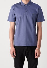 Polo tričko v tlumené fialové barvě, vyrobené z lehkého bavlněného materiálu. Obsahuje tříknoflíkovou légou, krátké rukávy a malou nášivku na prsou.