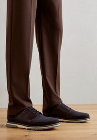 Dark navy shoes with mesh and leather materials, featuring a round toe and textured surface. The sole is light gray with a sporty design.