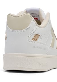 Białe sneakersy z beżowymi akcentami, górna część z gładkiej skóry, teksturowana podeszwa i branding "ST. POWER PLAY" po boku.