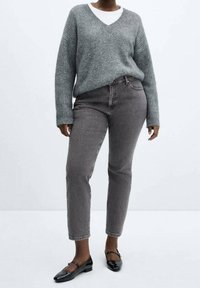 Suéter de punto acanalado gris con escote en V, combinado con jeans oscuros de talle alto y bailarinas negras. Diseño simple, tejido texturizado.