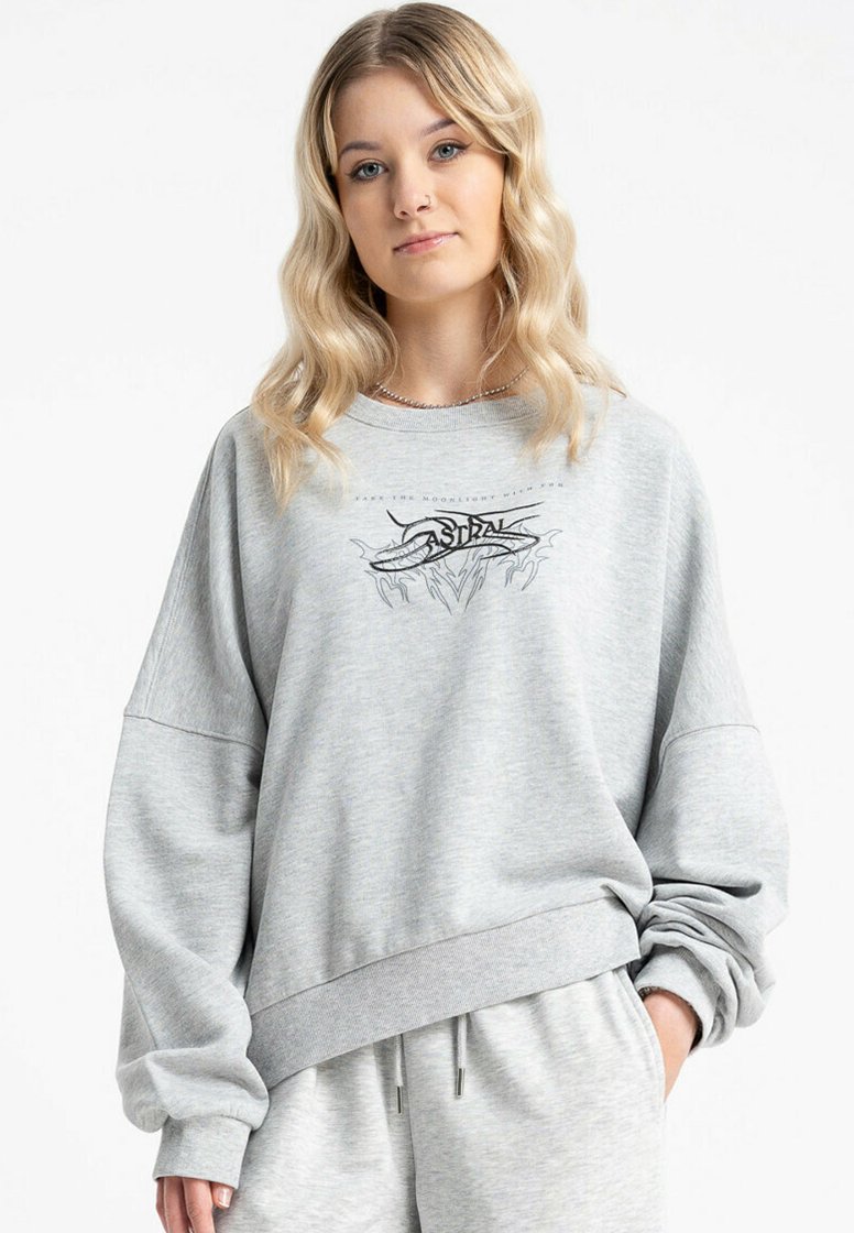 Szara bluza z luźnym krojem, oversize'owymi rękawami oraz graficznym nadrukiem. Wykonana z miękkiego materiału, z ściągaczami przy rękawach i u dołu.