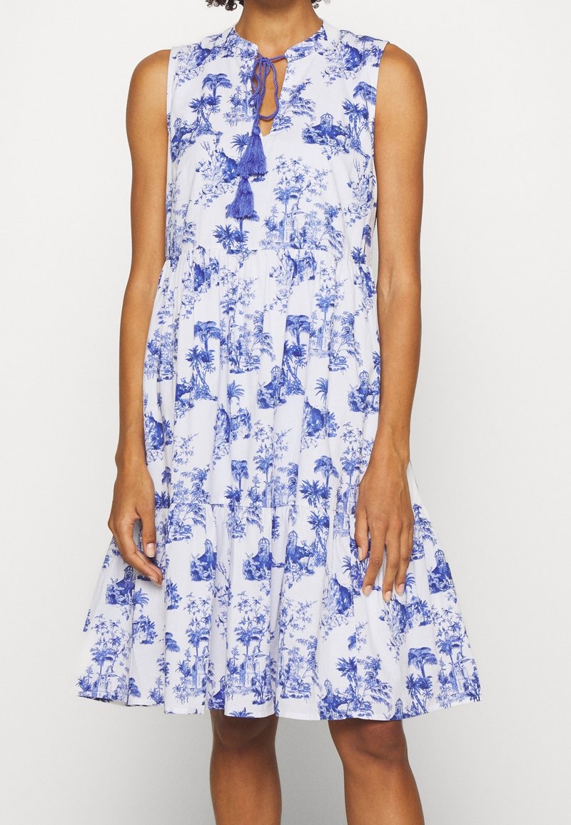 Robe sans manches bleue et blanche avec un col rond, dotée d'un cordon de serrage et d'une jupe fluide à volants, ornée d'un motif floral.