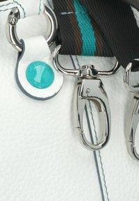 Sangle de sac en cuir blanc avec des accessoires en métal argenté. La sangle présente une surface texturée avec des accents rayés turquoise et marron.