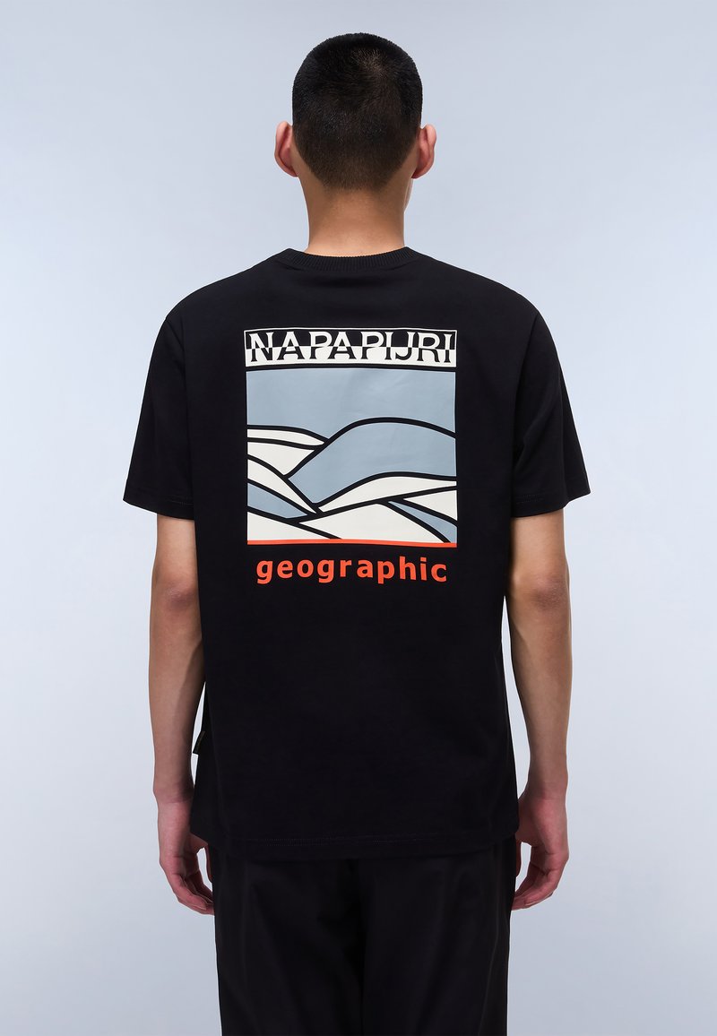 Tricou negru cu un design grafic pe spate, prezentând valuri geometrice albastre și albe și textul "NAPAPIJRI" deasupra cuvantului "geographic" în portocaliu.