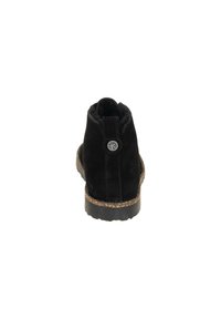 Botine negre din suede, cu vârf rotunjit, superior texturat, talpă intermediară din plută și un accent circular cu logo pe spate.