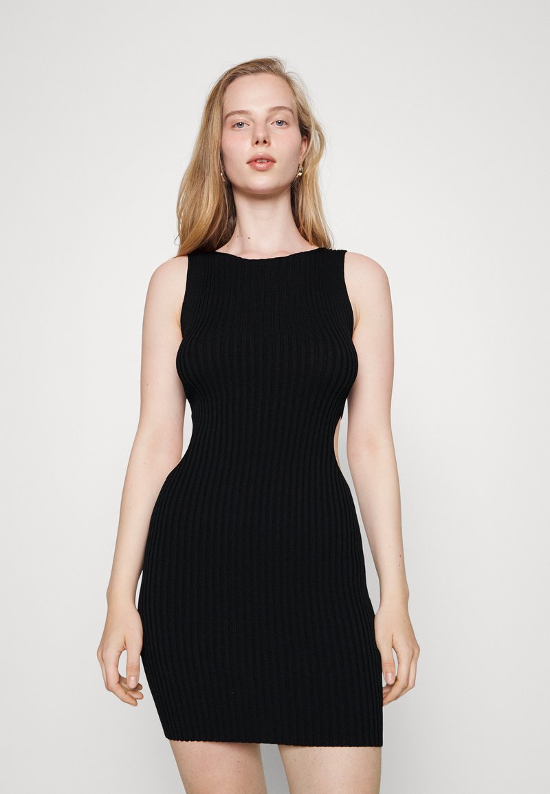 Vestido preto de malha canelada com silhueta ajustada, design sem mangas e decote barco. Possui recortes laterais e comprimento mini.