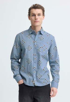 Chemise bleu clair à boutons avec motif floral découpé, dotée d'une poche poitrine et de manches longues. Fabriquée en tissu de coton pour le confort.