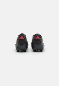 Black athletic shoes with a sleek design, featuring red accents and three red stripes on the heel. Textured upper and molded outsole.