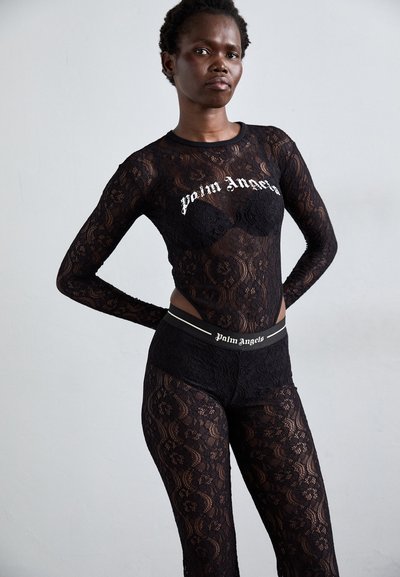 Schwarzer Spitzen-Body und Leggings mit floralen Mustern. Der Body hat lange Ärmel und einen runden Halsausschnitt sowie das Logo "Palm Angels".