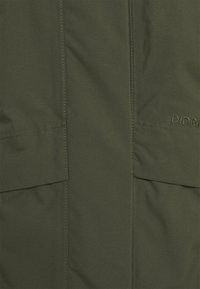 Veste vert olive avec une texture lisse, deux poches avant et un logo brodé discret. Coupe droite avec un design minimaliste.