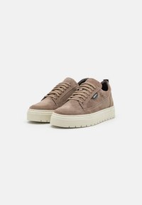 Para beżowych zamszowych sneakersów na sznurowadła z grubymi off-white gumowymi podeszwami na tle białego tła.