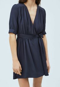Námořnické zavinovací šaty z lehké tkaniny, s krátkými ohrnutými rukávy, hlubokým V-výstřihem a páskem na zavázání v pase, s volným siluetem.