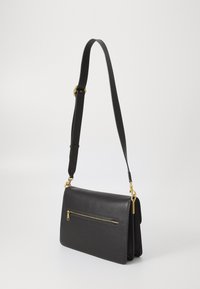 Sac à épaule en cuir noir avec une texture lisse, une poche zippée sur le devant, des accents en métal doré et une bandoulière réglable.