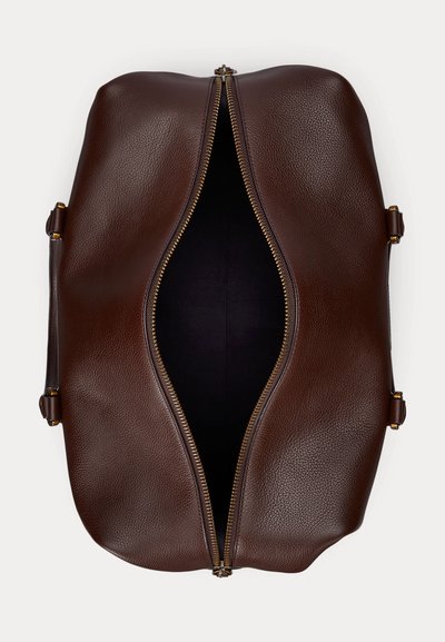 Brūna ādas duffle soma ar daļēji atvērtu zelta rāvējslēdzēju, redzams tukšs melns iekšpuse, skatīts no augšas uz balta fona.