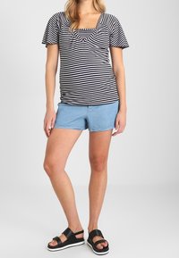 Black and white striped top with short sleeves, square neckline; paired with light blue denim shorts and black sandals with a platform sole.