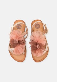 Sandalias de tul rosa y marrón con una correa metálica, plantilla acolchada y hebilla ajustable. Suela plana con bordes cosidos.