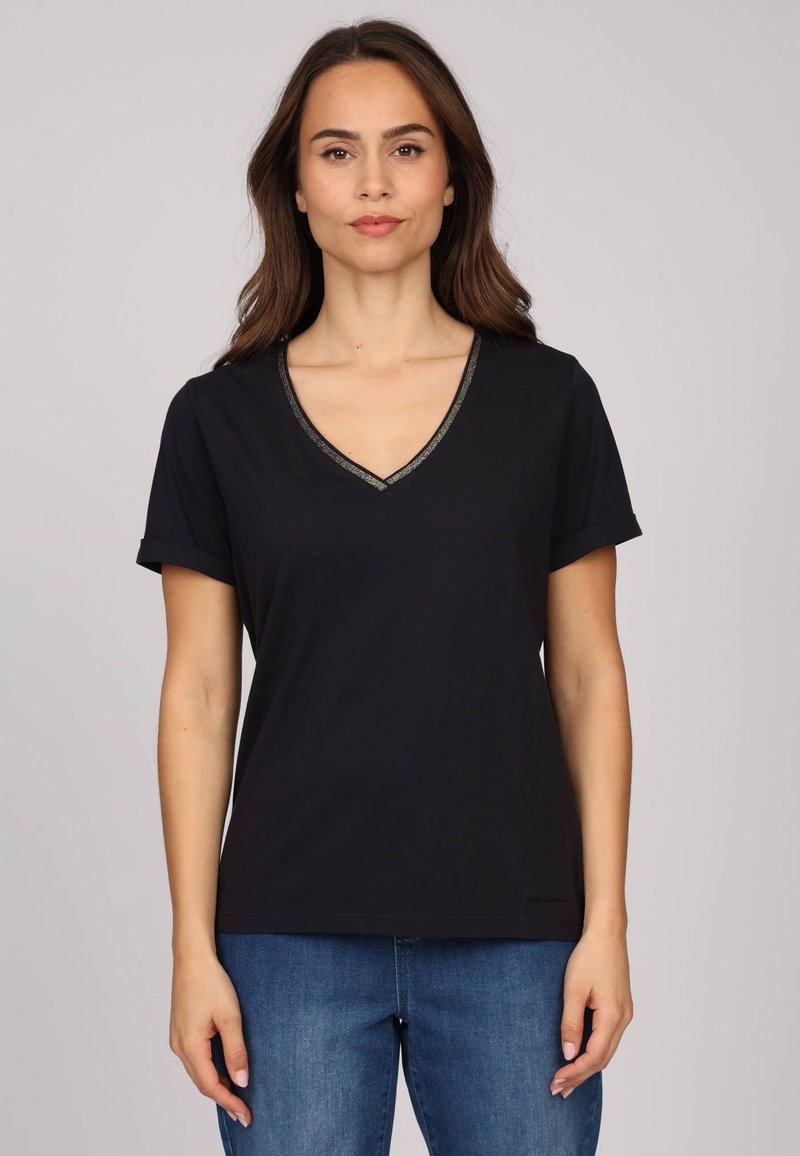 T-shirt noir à col en V fabriqué en tissu doux, avec des manches courtes roulées et une bordure métallique décorative le long de l'encolure.