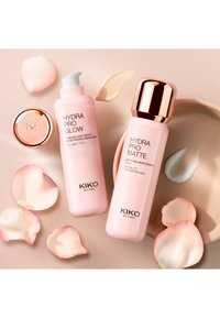 To rosa KIKO Milano Hydra Pro hudpleieflasker med kremprøver, rosenblader og en gullhette på en beige overflate.