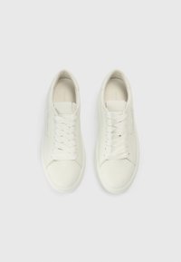 Λευκά δερμάτινα αθλητικά παπούτσια με λείο φινίρισμα, στρογγυλεμένη μύτη και επίπεδα κορδόνια. Μινιμαλιστικός σχεδιασμός με ραμμένο μοτίβο στα πλαϊνά.