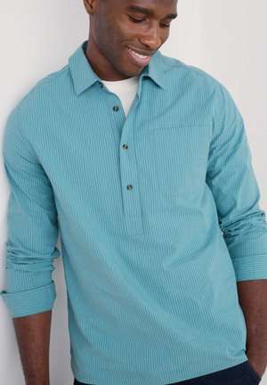 Light blue striped long-sleeve shirt with a buttoned collar, single chest pocket, and rolled cuffs. Fabric appears smooth and lightweight.