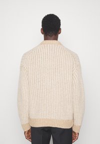 Beige gestrickter Pullover mit einem strukturierten Muster, gerippten Bündchen und Saum. Verfügt über einen runden Kragen und ein lässiges Design.