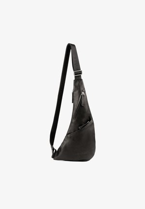 Black leather sling bag with a curved design, featuring two zippered compartments and an adjustable strap with embossed branding.
