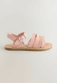 Sandali rosa con cinghie e suola piatta. Presentano una cinghia alla caviglia regolabile con una fibbia in argento e una soletta di colore naturale.