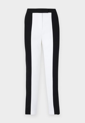 Black and white tapered trousers featuring a slim fit with contrasting panels. Fabric has a smooth texture; waistband is flat and fitted.