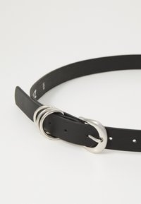 Black leather belt featuring a silver metal buckle, three decorative rings, and multiple holes for size adjustment. Smooth texture.