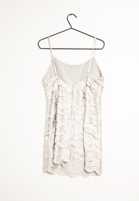 Ljusgrå slipklänning med tunna band, med en vågig, lager-på-lager volangdesign och scalloperade kanter genom hela tyget.