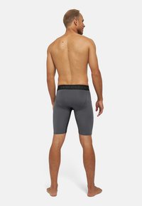 Männer graue Sportshorts mit schwarzem Bund und dem Schriftzug "DANISDURANCE"; glattes, enges Design mit Seitentaschen.