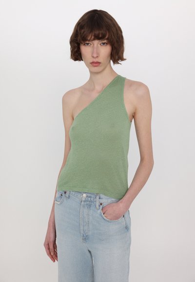 Grön, en-axlad topp i ett lätt, strukturerat tyg. Kombination med ljusblå, högmidjade jeans.