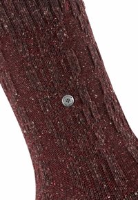 Calze lavorate a maglia in un profondo bordeaux con un motivo testurizzato, caratterizzate da un piccolo bottone metallico con logo vicino alla caviglia.