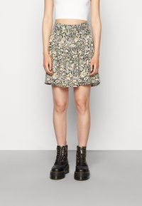 Saia de padrão floral com cintura elástica e bainha com babados. Combinada com botas pretas com atacadores e sola grossa.