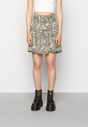 Saia de padrão floral com cintura elástica e bainha com babados. Combinada com botas pretas com atacadores e sola grossa.