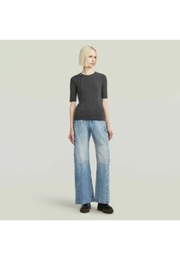 Top gri ajustat cu maneci scurte, asociat cu blugi de denim ușor albastri, cu picioare largi, având panouri din patchwork și cusături contrastante.