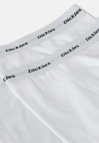 Hvite bomullsundertøy med en grå midje med svart "Dickies"-logo. Glatt tekstur, standardpassform, og ingen synlige mønstre eller detaljer.