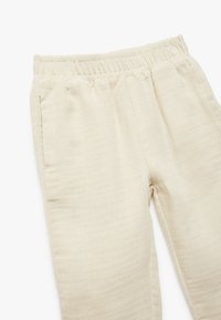 Beige soft fabric broek met een elastische tailleband, voorzien van zijzakken en een relaxte pasvorm, met een gladde en lichte textuur.