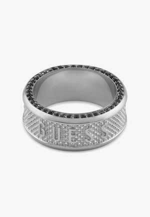 Zilveren ring met een gestructureerde band, gekenmerkt door een gegraveerd "GUESS" en een zwarte edelsteenrand. Gladde binnenafwerking, modern ontwerp.