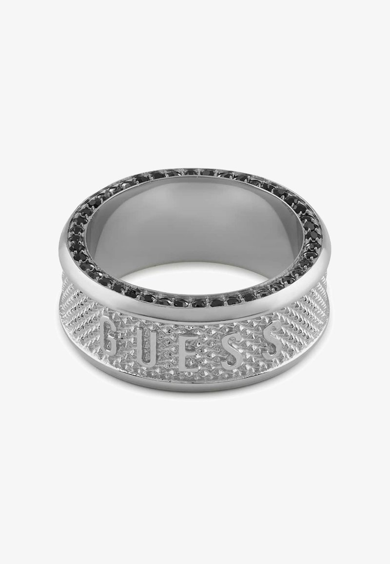 Zilveren ring met een gestructureerde band, gekenmerkt door een gegraveerd "GUESS" en een zwarte edelsteenrand. Gladde binnenafwerking, modern ontwerp.