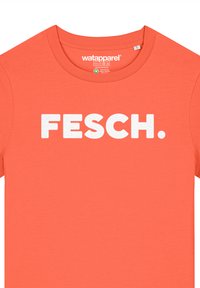 Koraalrood katoenen T-shirt met een ronde hals en korte mouwen. Voorzien van vetgedrukte, witte blokletters met de tekst "FESCH."