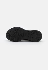 Sole di scarpa da ginnastica nera con grip testurizzati, battistrada a motivi e scanalature flessibili per aderenza e supporto. Materiale in gomma resistente.
