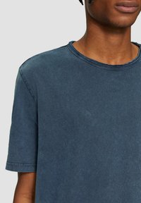 Korte mouwen crewneck t-shirt in donkerblauw, gemaakt van zachte katoen. Heeft een licht vervaagde textuur met zichtbare stiksels rond de hals.