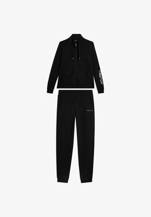 Sweat à capuche noir zippé avec poches latérales et pantalon de jogging noir assorti, tous deux portant la marque "FREDDY" sur la manche et la jambe.