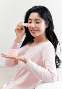 Maglione rosa a coste, barattolo trasparente con etichetta "Abib PDRN Collagen Overnight Mask", donna che applica gel con spatola bianca, pelle liscia, illuminazione soffusa.