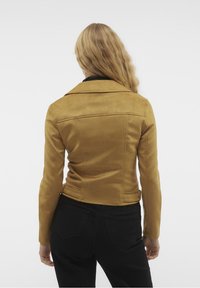 Tan suède jas met een aansluitend ontwerp, nikkelhals en een gladde textuur. Voorzien van zijzakken en een cropped zoom.