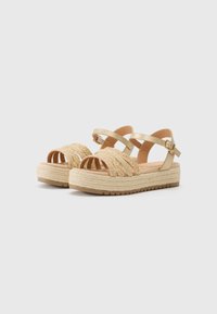Gold strappy sandals with braided textile upper, espadrille-style jute platform, and buckle closure. Rubber outsole for grip.