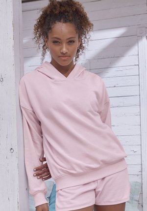 Lichtroze hoodie met een relaxte pasvorm en diepe V-halslijn, gecombineerd met bijpassende shorts. Gemaakt van zachte stof met ribgebreide manchetten en zoom.