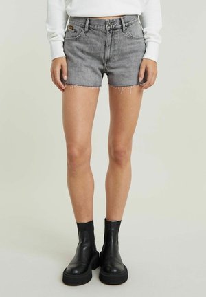 Gray denim shorts with a frayed hem, five-pocket design, and belt loops, worn with black ankle boots featuring chunky soles.